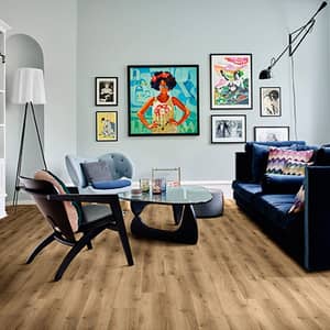 Brauner Vinylboden in Holzoptik in einem Wohnzimmer mit Dunkelblauer Couch, zwei sesseln und einem Glastisch