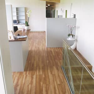 Hellbrauner Vinylboden in Holzoptik in einem Flur mit einer kleinen Theke links und rechts einer Treppe, die nach unten führt