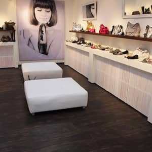 Dunkelbrauner Vinylboden in einem Verkaufsraum mit Regalen an der Wand, wo Schuhe und Taschen drin stehen